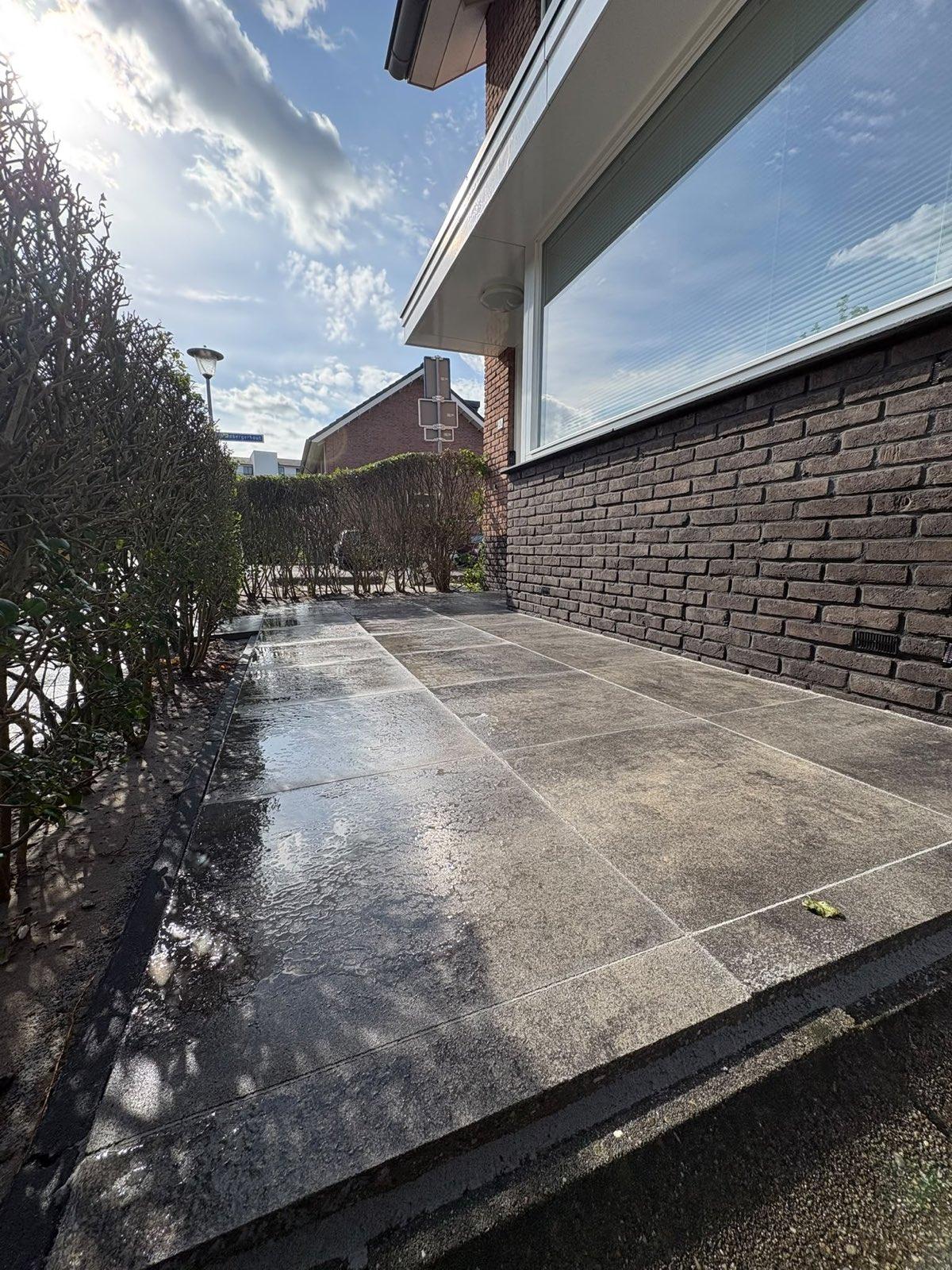 Zijpad langs de woning in keramische tegels aangelegd door Franke Tuinen