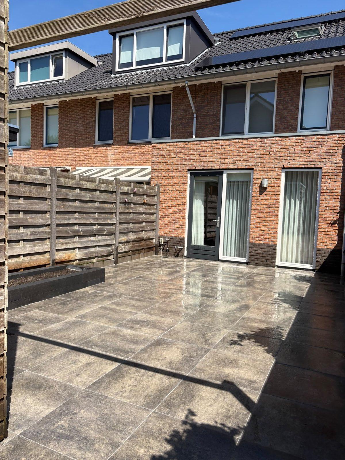Keramisch terras met verdiepte plantenbak en pergola aangelegd door Franke Tuinen