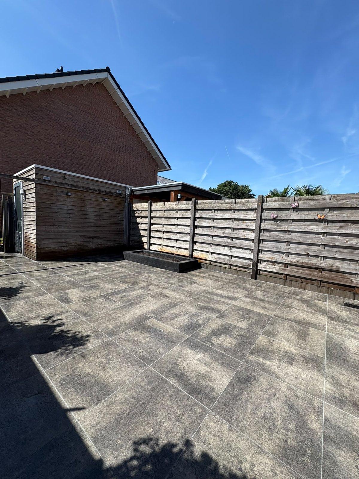 Keramisch terras langs de gevel met verdiepte border aangelegd door Franke Tuinen